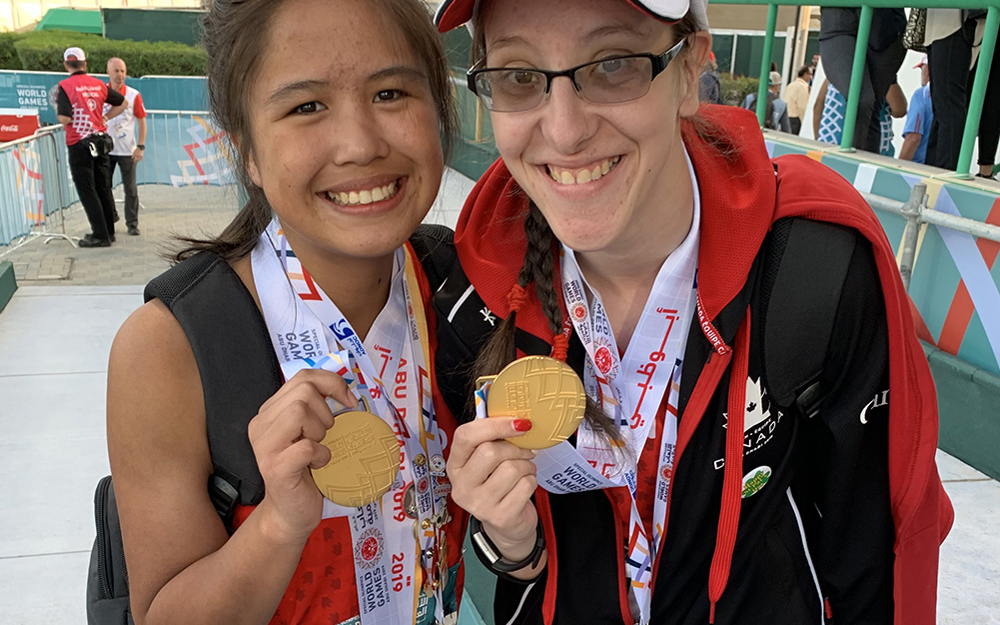 Two Special Olympics BC athletes pose for the camera with their gold medals received in track and field.