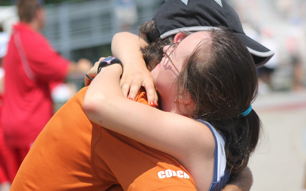 Special Olympics BC athlete embraces their coach in a warm hug after their event.