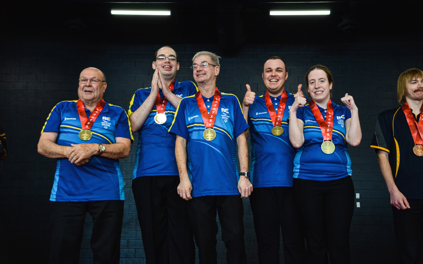Five athletes with intellectual disabilities proudly stand together with their gold medals hung around their necks. 