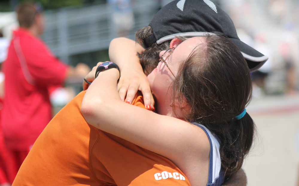 Athlete and coach hug