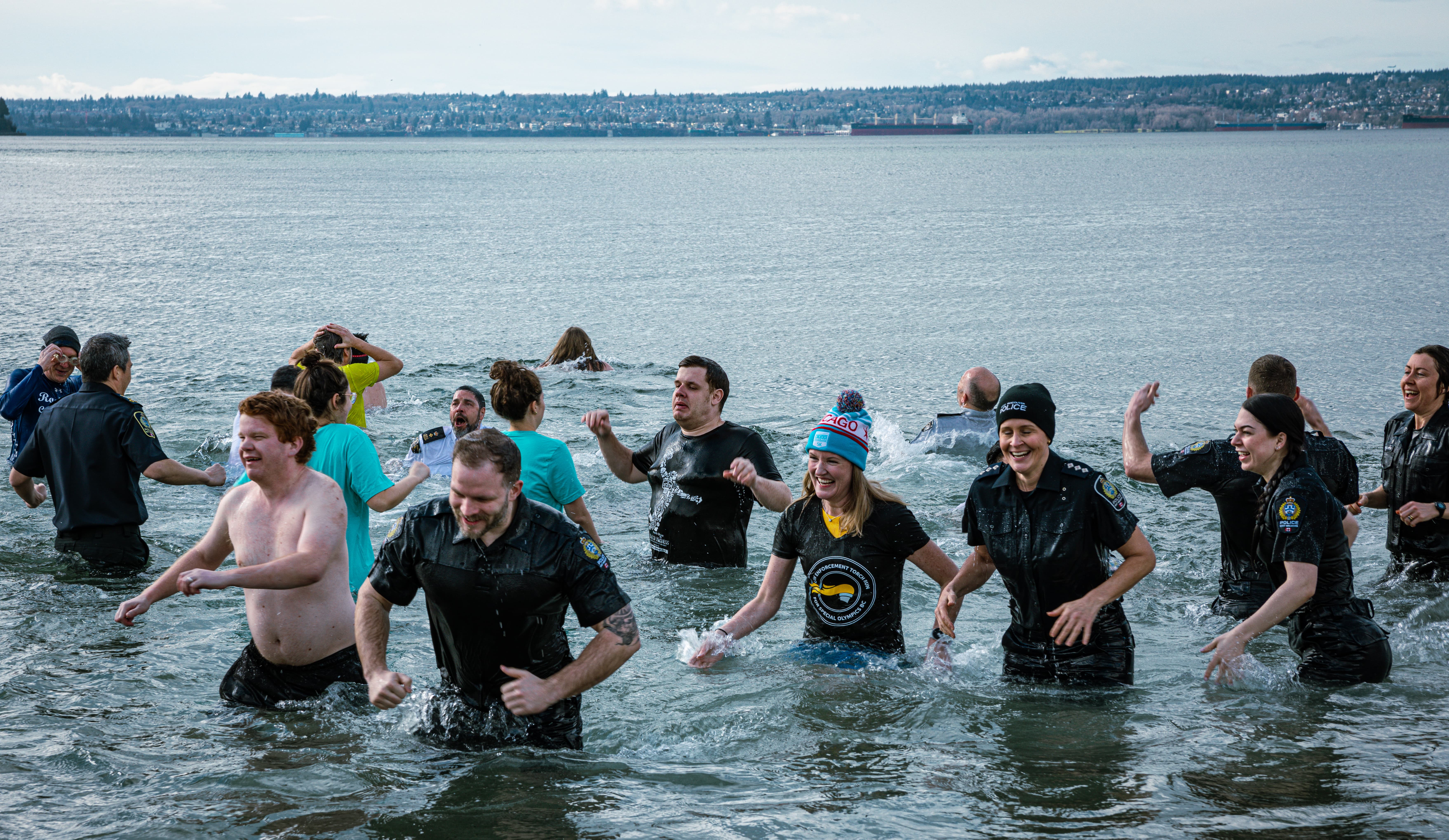 A large group of Law Enforcement Torch Run Polar Plunge participants wade out of the frigid waters with smiles on their faces. A large group of Law Enforcement Torch Run Polar Plunge participants wade out of the frigid waters with smiles on their faces.