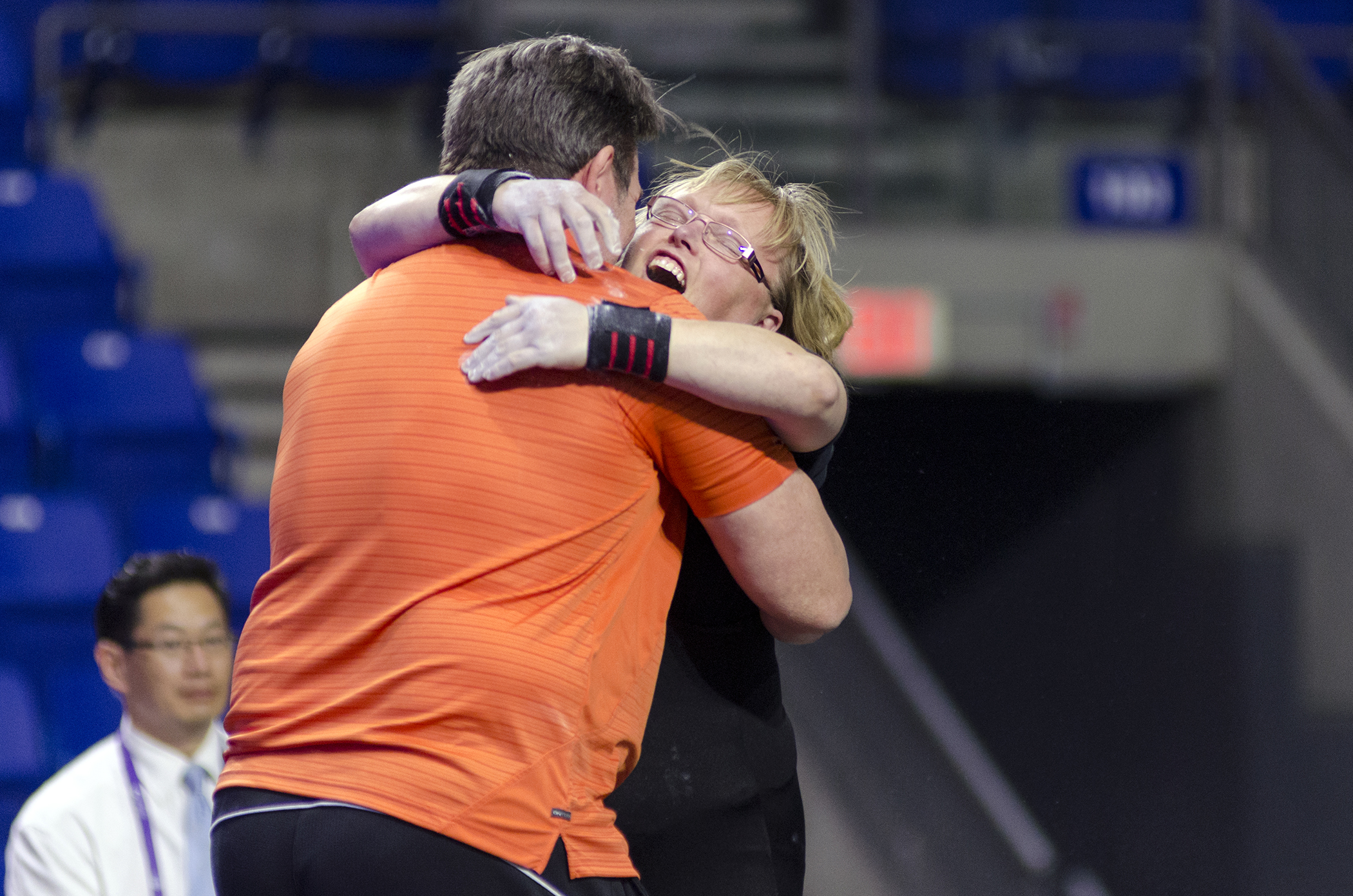 A coach and powerlifting athlete embrace at a competition. A coach and powerlifting athlete embrace at a competition.